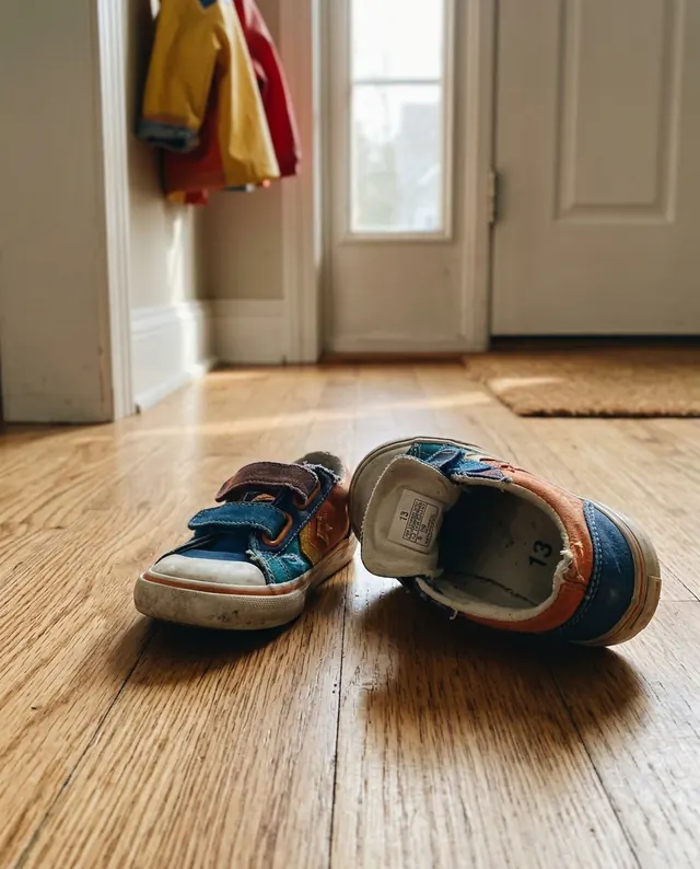 A child's sneakers on a wooden floor, size 13 printed inside